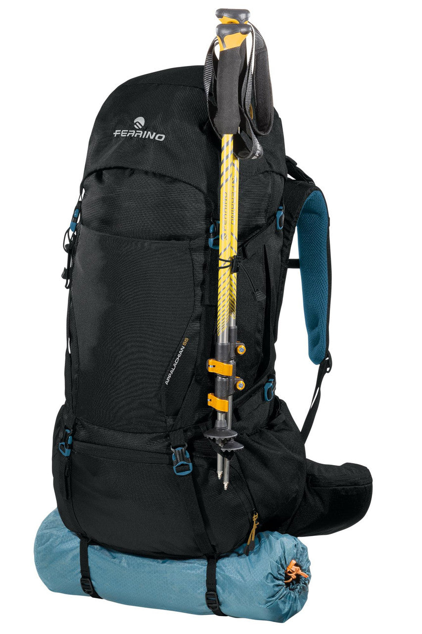Mochila Ferrino Apalachian 55 con saco de dormir y bastones de trekking sujetos en la parte frontal. negra