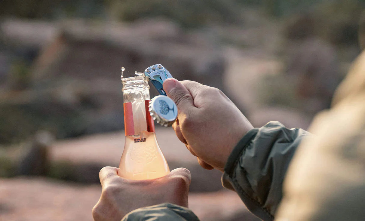 Leatherman Skeletool KB en uso utilizando la función abrebotellas en entorno outdoor o de viaje