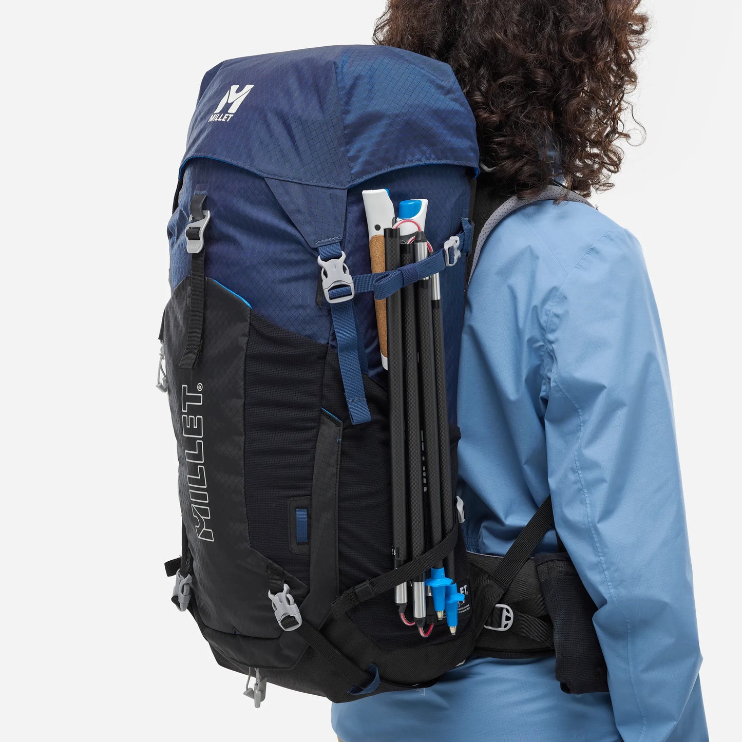 mochila Millet Ubic 30L mujer con bastones de trekking sujetos en el exterior
