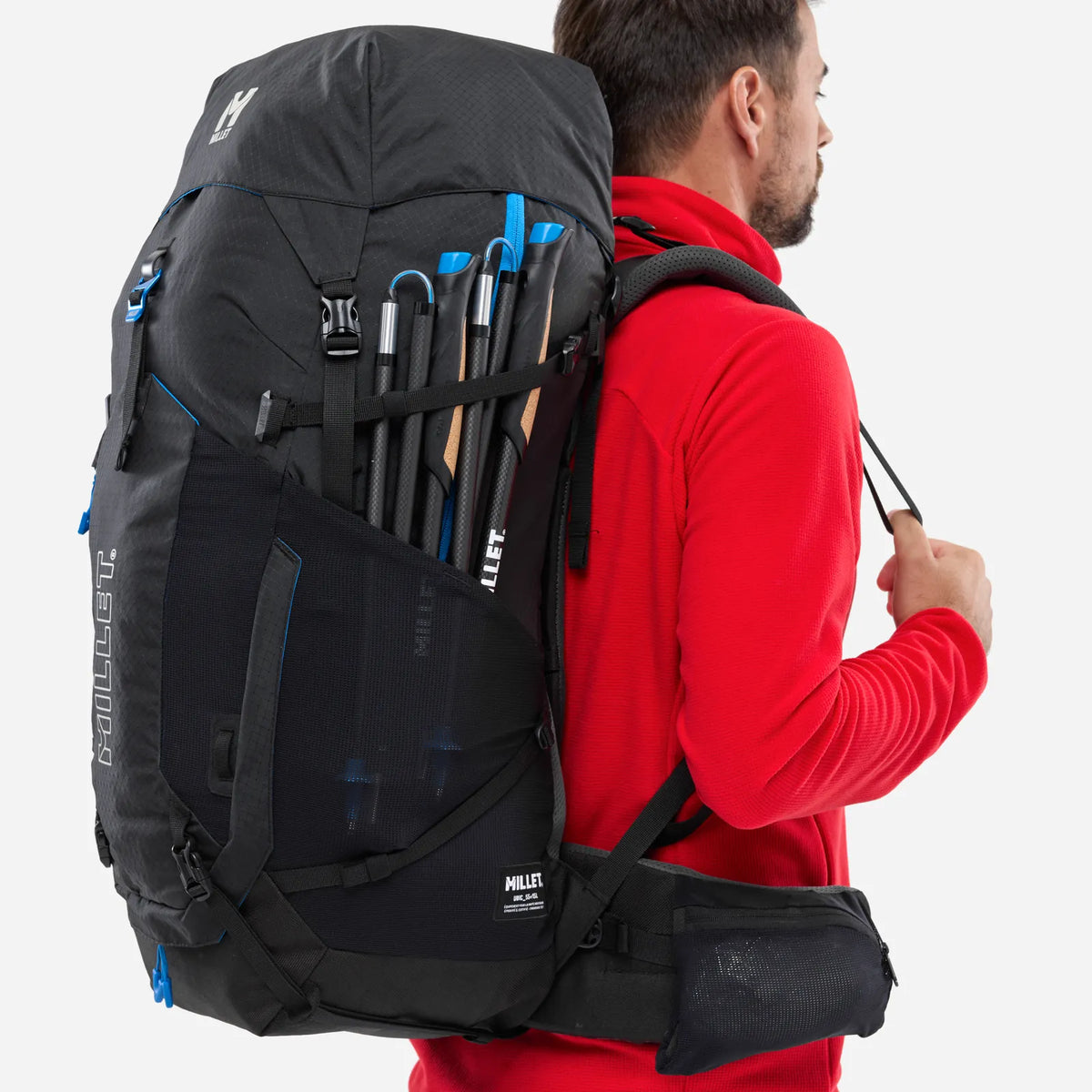 mochila Millet Ubic 55+15 con bastón de trekking sujeto en el exterior