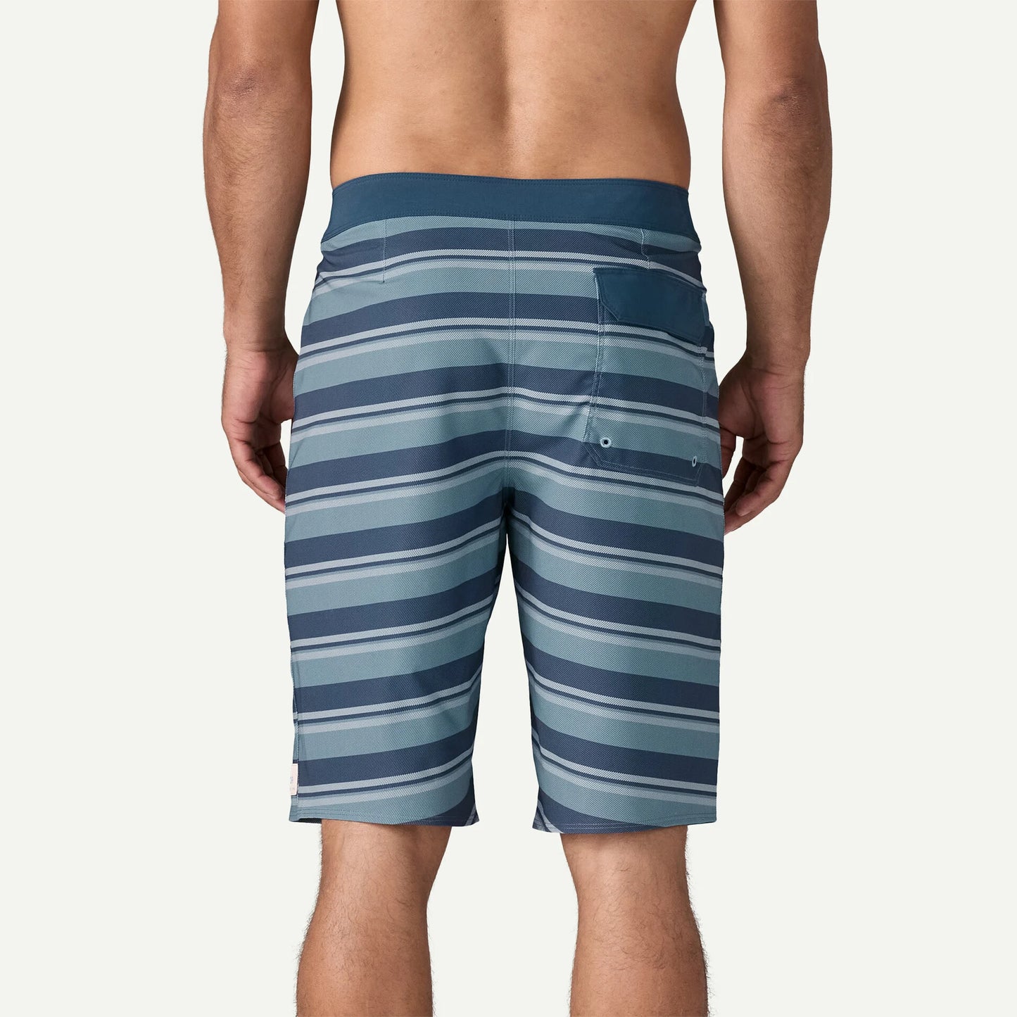 Hombre de espaldas usando Patagonia M’s Hydropeak Boardshorts Twinnie Stripe Still Blue en entorno de playa y verano activo